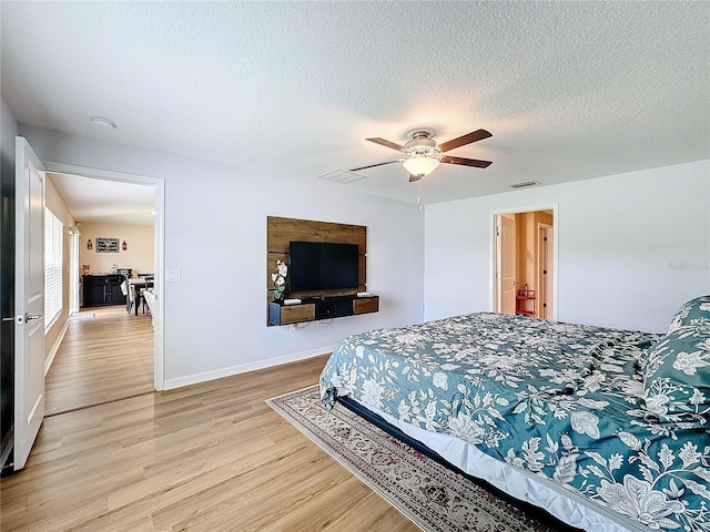 bedroom featuring ceiling fan, light hardwood / wood-style floors, and a textured ceiling