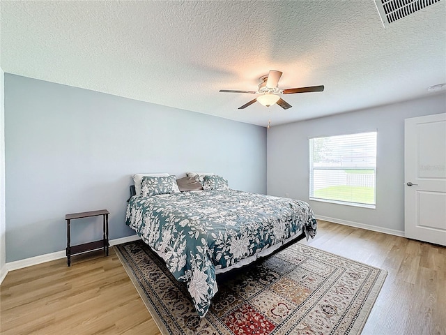 bedroom with ceiling fan, a textured ceiling, and light hardwood / wood-style flooring