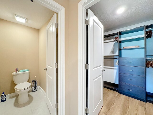 bathroom with hardwood / wood-style floors, a textured ceiling, and toilet