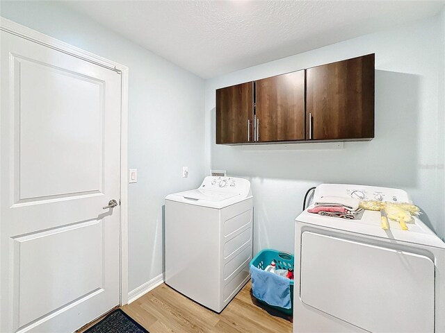 laundry area featuring cabinets, independent washer and dryer, a textured ceiling, and light hardwood / wood-style flooring