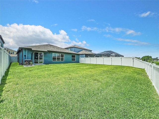 rear view of house with central AC unit and a lawn