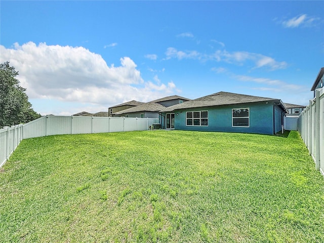 back of house with central AC and a yard