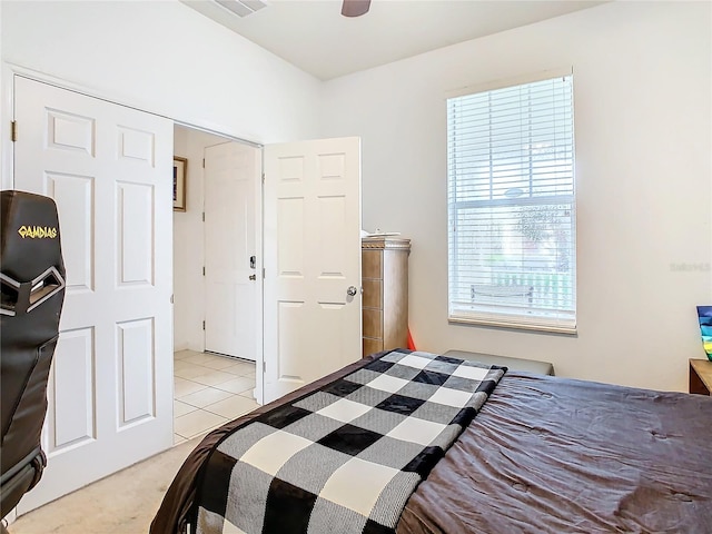 bedroom featuring a closet, light carpet, multiple windows, and ceiling fan