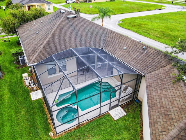 view of pool with central air condition unit, a lawn, and glass enclosure