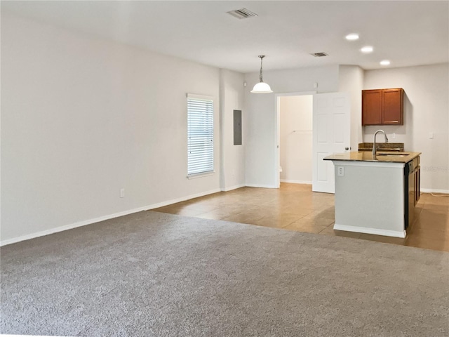 kitchen featuring light carpet, electric panel, sink, hanging light fixtures, and an island with sink