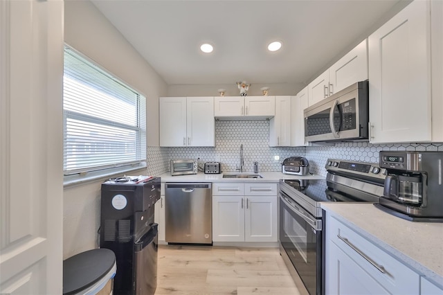 kitchen featuring sink, white cabinetry, stainless steel appliances, and tasteful backsplash