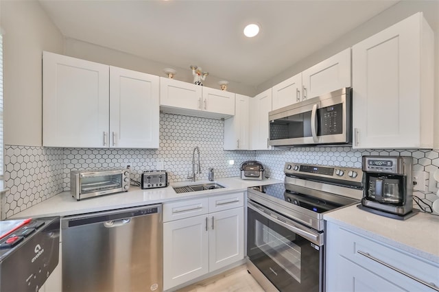 kitchen with decorative backsplash, sink, white cabinets, and stainless steel appliances