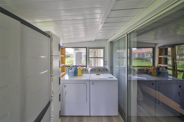 clothes washing area with washer and clothes dryer and light hardwood / wood-style flooring