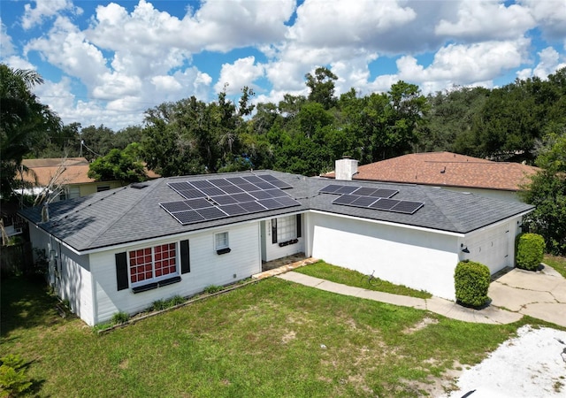 view of front of home with a garage, a front lawn, and solar panels