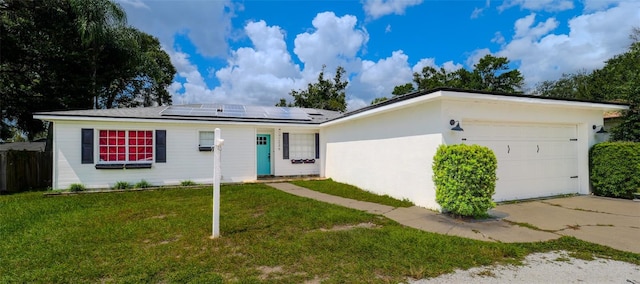 ranch-style home featuring a garage, solar panels, and a front lawn