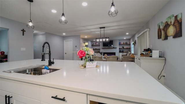 kitchen featuring pendant lighting, white cabinets, and sink