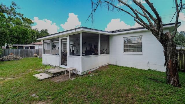 rear view of house with a sunroom and a yard