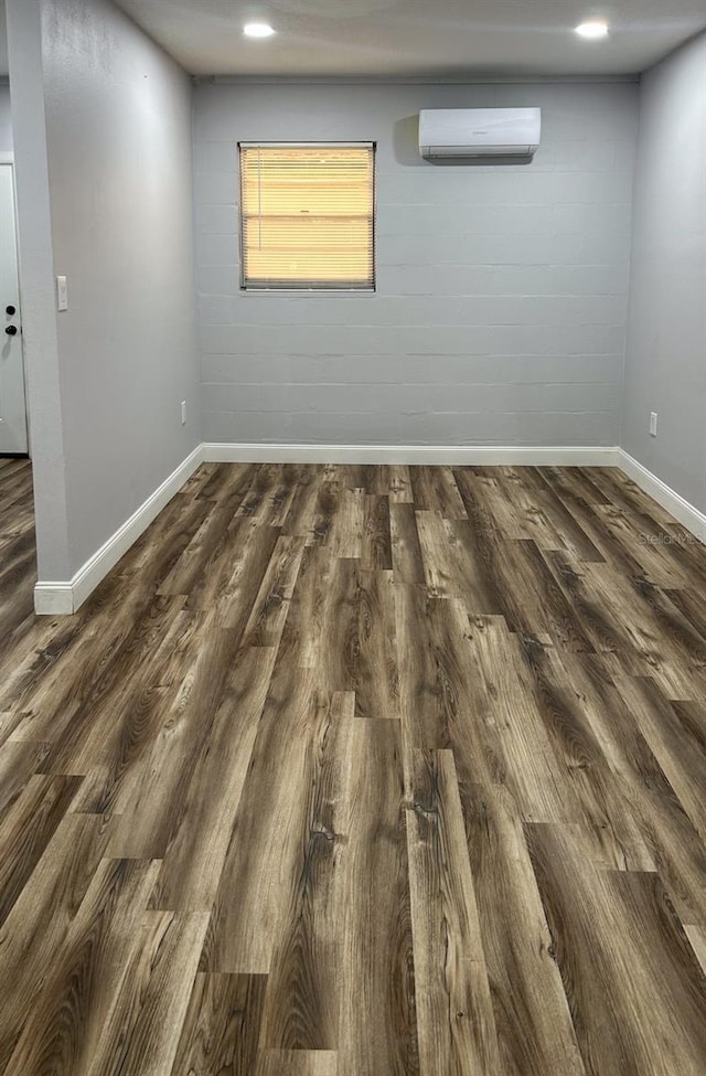 spare room with an AC wall unit and dark hardwood / wood-style flooring