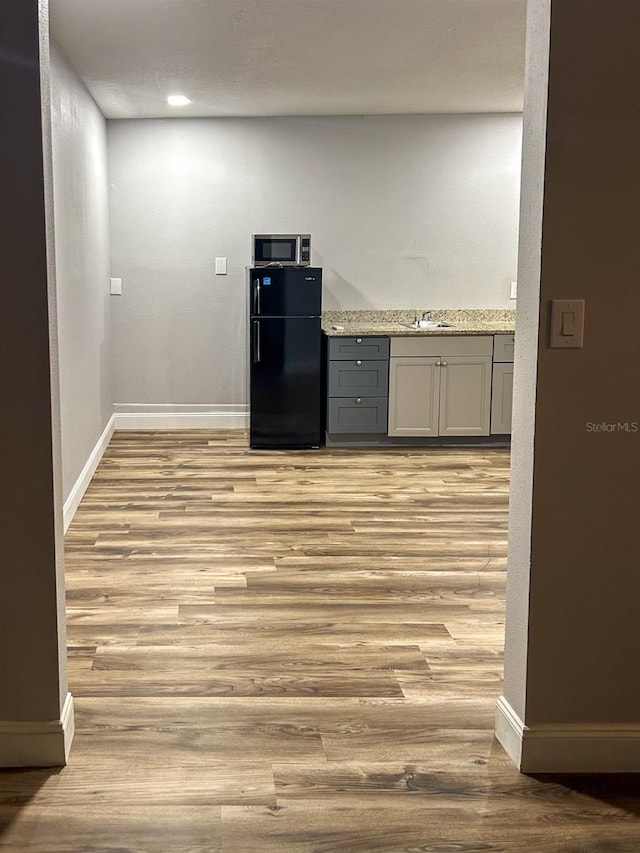 kitchen featuring black fridge, gray cabinets, light wood-type flooring, and sink