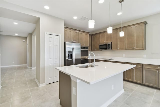 kitchen with sink, decorative light fixtures, a center island with sink, light tile patterned flooring, and appliances with stainless steel finishes