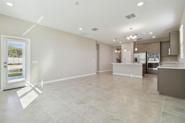 unfurnished living room with a notable chandelier, light tile patterned floors, and sink