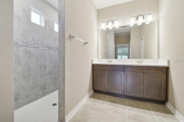 bathroom with tile patterned flooring, vanity, and tiled shower