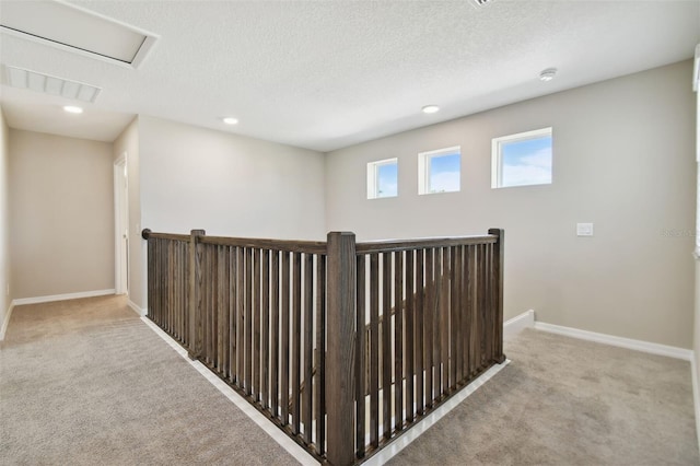 corridor featuring a textured ceiling and light colored carpet