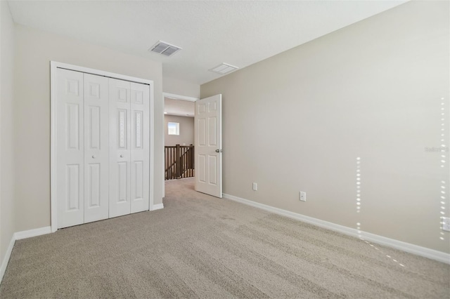 unfurnished bedroom with light colored carpet and a closet