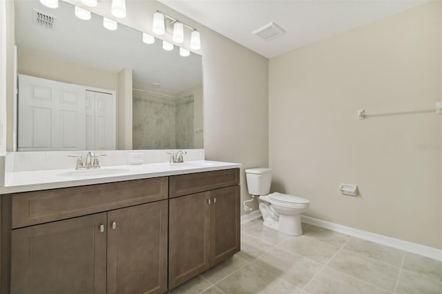 bathroom with tile patterned flooring, a tile shower, vanity, and toilet