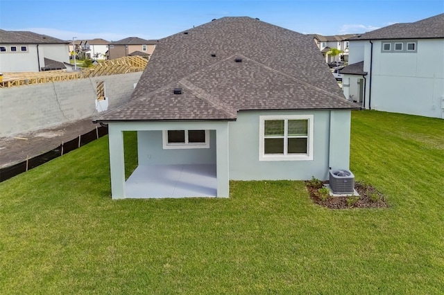 rear view of house with a patio, cooling unit, and a lawn