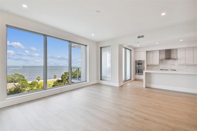 unfurnished living room featuring light wood-type flooring and a water view