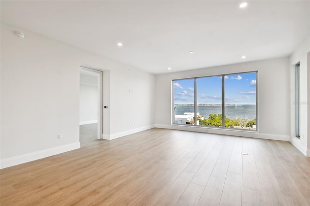 unfurnished room featuring a water view and light hardwood / wood-style floors