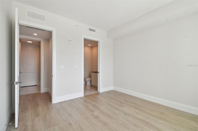 unfurnished bedroom featuring light wood-type flooring and ensuite bath