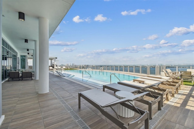 view of pool featuring a water view and a patio area