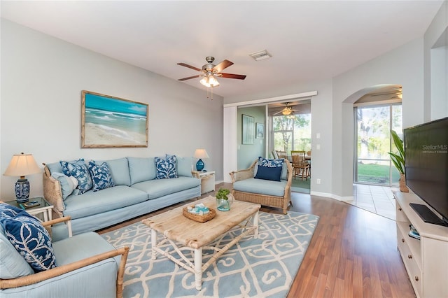 living area with arched walkways, visible vents, ceiling fan, and wood finished floors