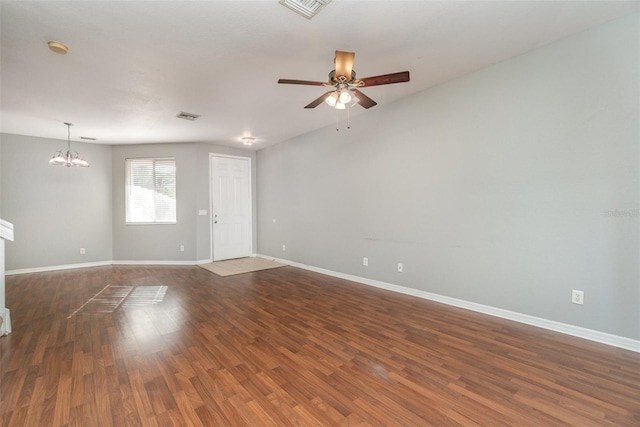 empty room featuring visible vents, dark wood finished floors, baseboards, and ceiling fan with notable chandelier