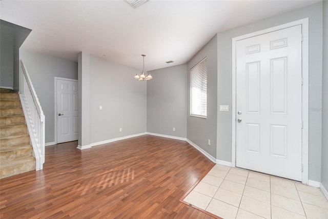 entrance foyer featuring a chandelier, visible vents, baseboards, stairs, and light wood-type flooring