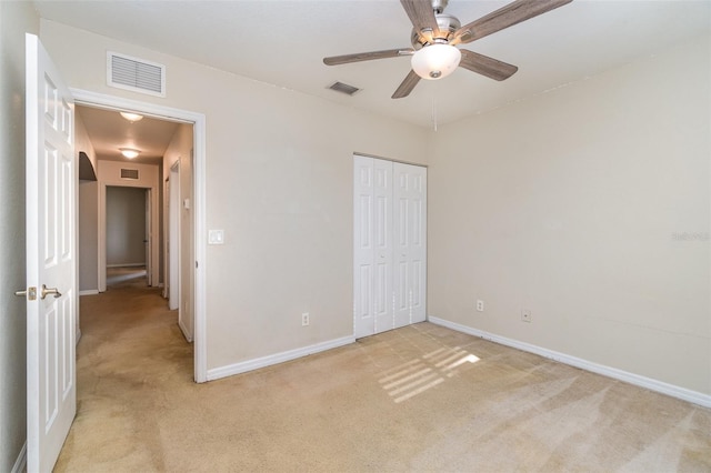 unfurnished bedroom with light carpet, a closet, visible vents, and baseboards