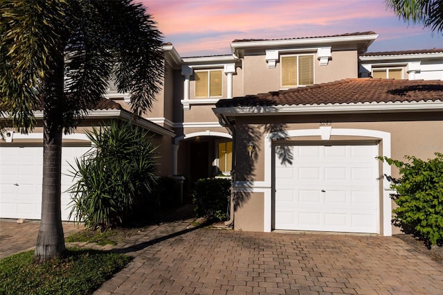 view of front of house with decorative driveway, a tile roof, and stucco siding