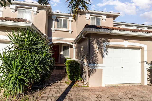 view of front of house with decorative driveway, a tiled roof, and stucco siding