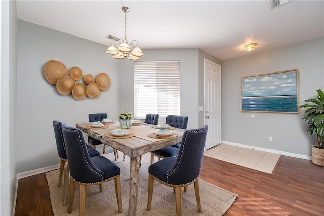 dining area with baseboards, visible vents, a notable chandelier, and wood finished floors