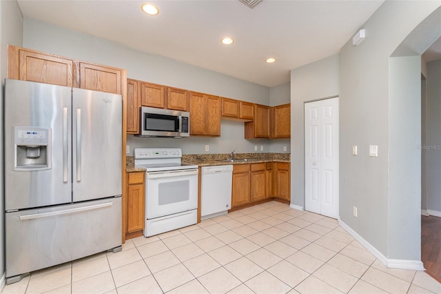 kitchen with arched walkways, baseboards, stainless steel appliances, a sink, and recessed lighting