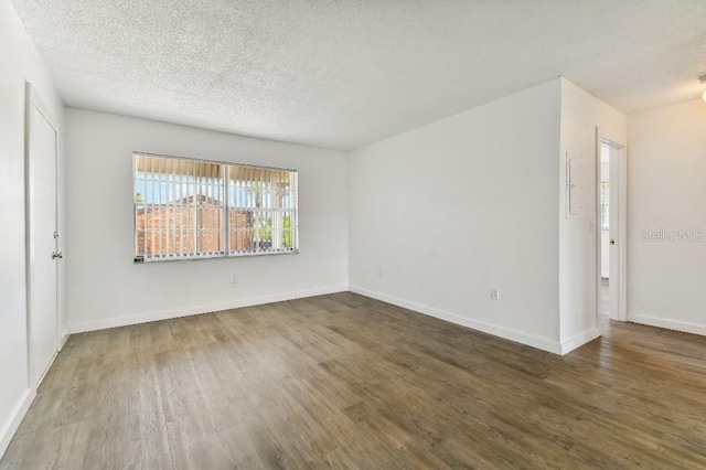 spare room with a textured ceiling and dark wood-type flooring