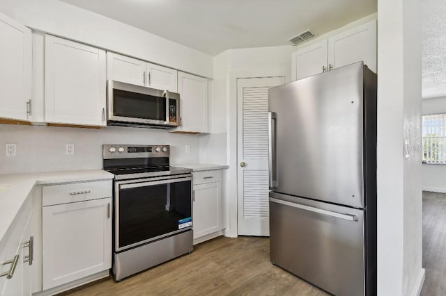 kitchen featuring appliances with stainless steel finishes, light hardwood / wood-style flooring, and white cabinetry