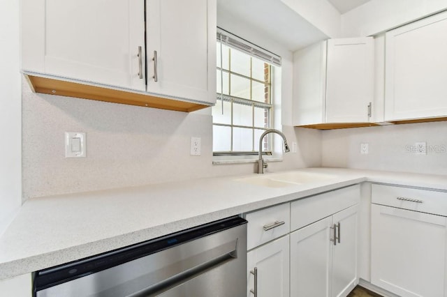 kitchen with stainless steel dishwasher, sink, and white cabinetry