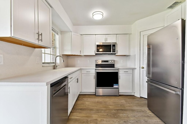 kitchen featuring appliances with stainless steel finishes, light wood-type flooring, sink, and white cabinetry