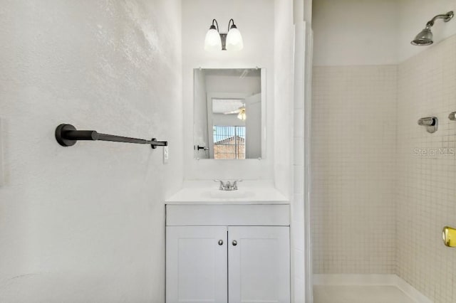 bathroom with a tile shower and vanity