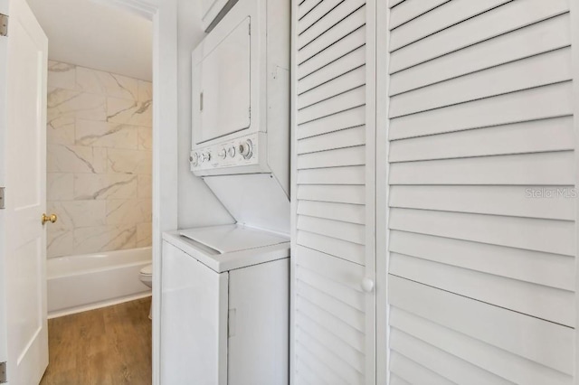 laundry area with stacked washer / dryer and wood-type flooring