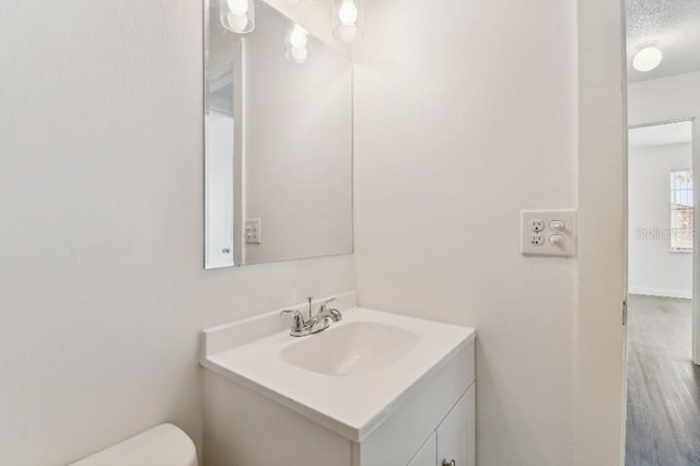 bathroom with a textured ceiling, toilet, vanity, and hardwood / wood-style flooring