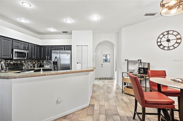 kitchen with decorative backsplash, appliances with stainless steel finishes, and light hardwood / wood-style floors