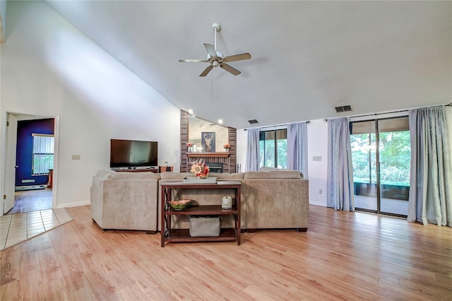 living room featuring a brick fireplace, high vaulted ceiling, light hardwood / wood-style flooring, and ceiling fan