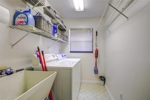 clothes washing area with washing machine and dryer, sink, and a textured ceiling