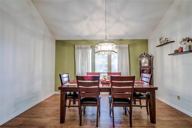 dining room featuring hardwood / wood-style floors, lofted ceiling, and a notable chandelier