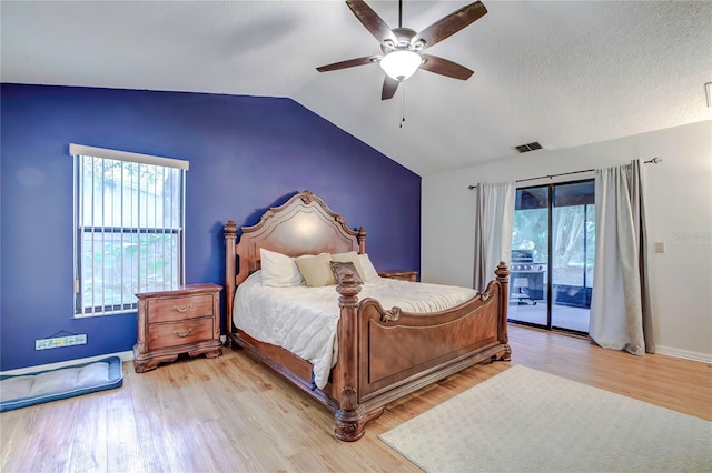 bedroom featuring light wood-type flooring, lofted ceiling, access to exterior, ceiling fan, and a textured ceiling