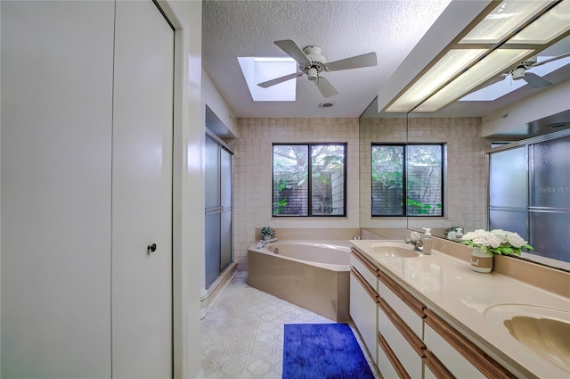 bathroom with ceiling fan, independent shower and bath, a textured ceiling, and a skylight